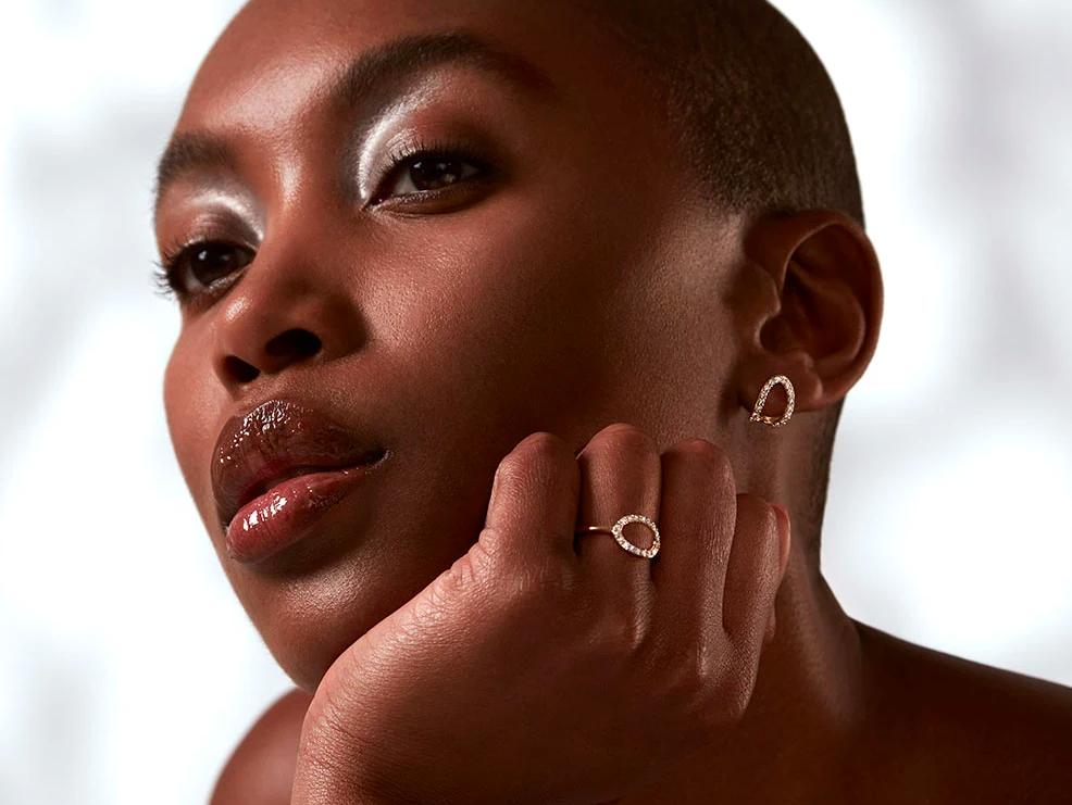 Women modelling gold halo commitment ring with matching cuff earrings