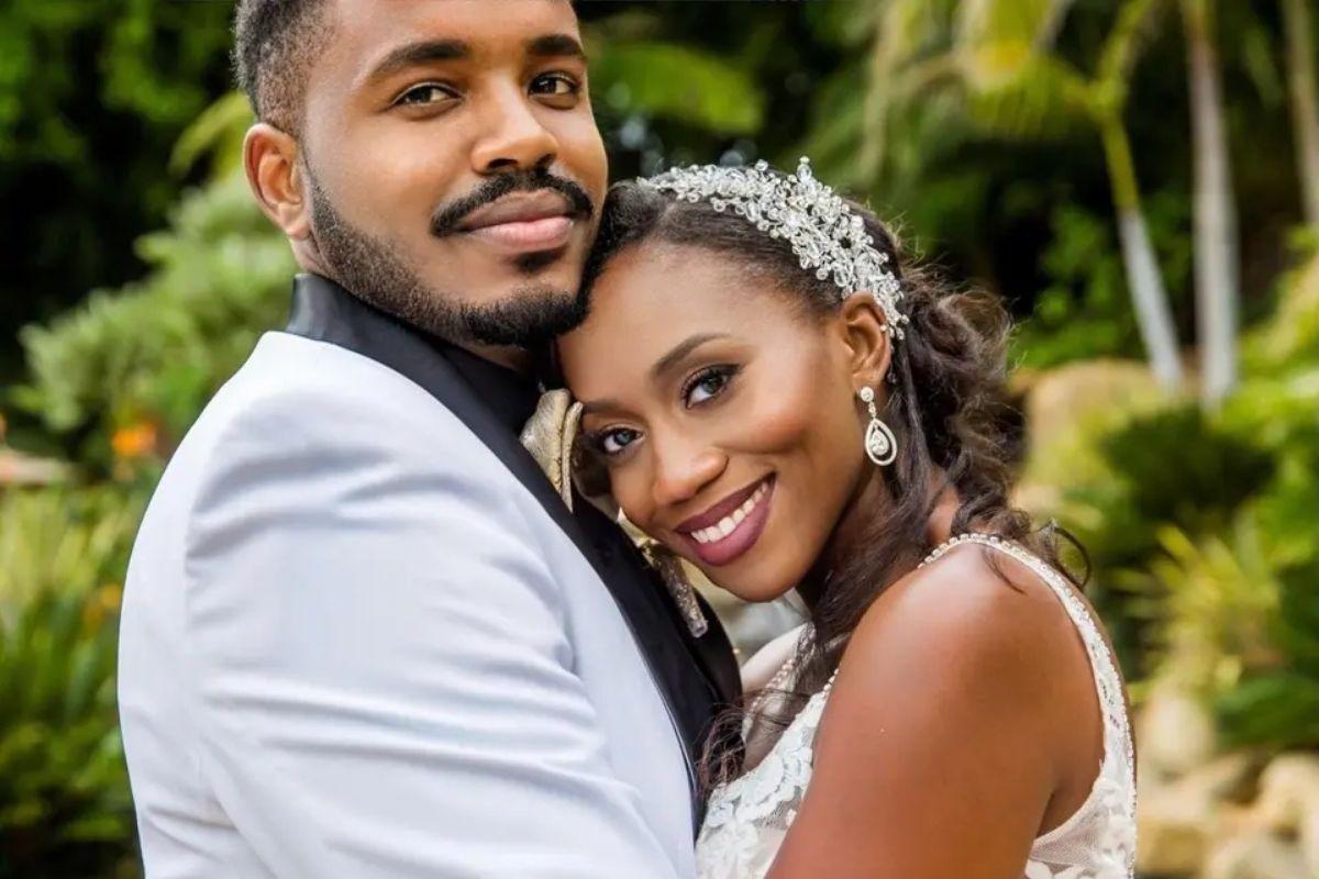 a bride and groom position their heads together as they smile on their wedding day with greenery in the background