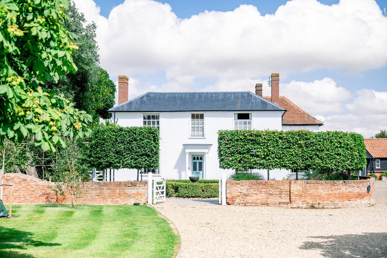 Exterior of georgian wedding venue vaulty manor showing a brick wall, hedges and a gravel drive in front of a double fronted house