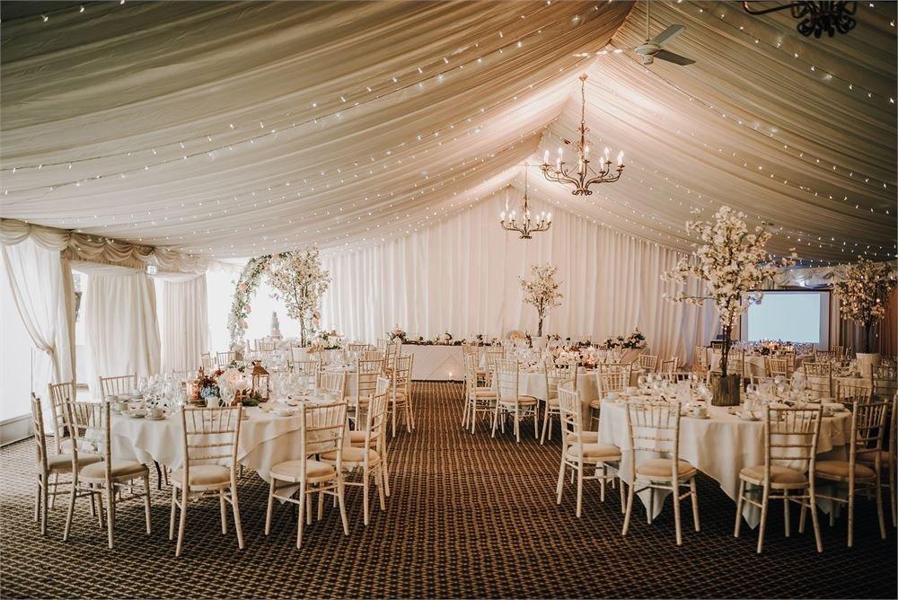 Fairy-lit marquee wedding venue at Audleys Wood Hotel, Hampshire with floral centrepieces and manicured gardens