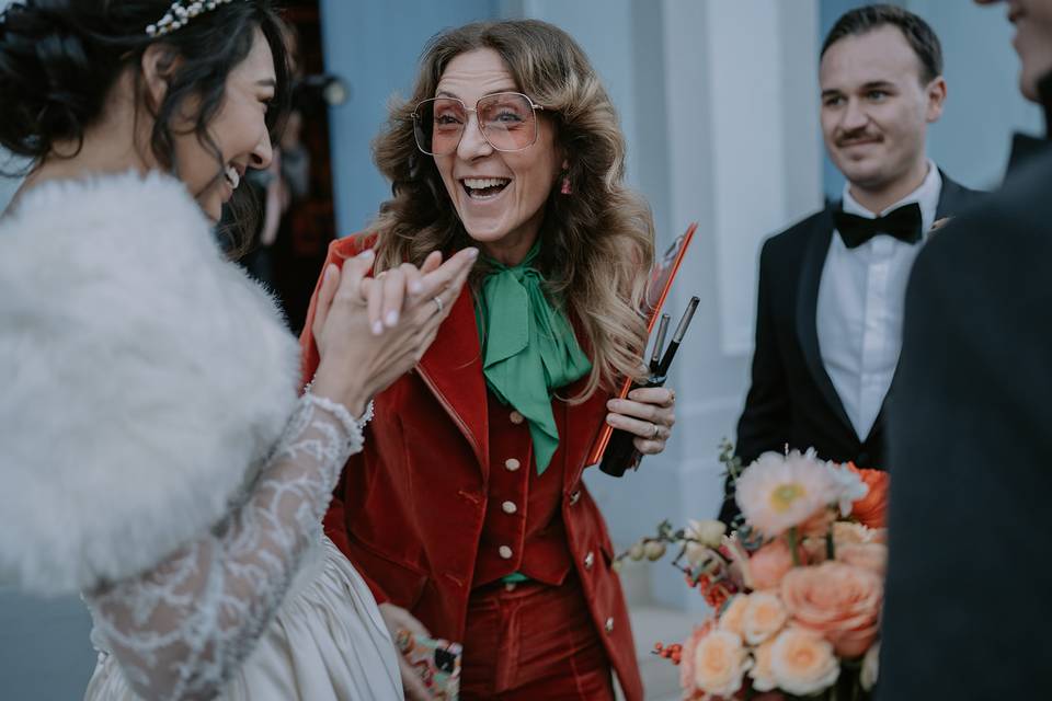 Zuza wedding planner wearing a red jacket and green shirt laughing with her couples