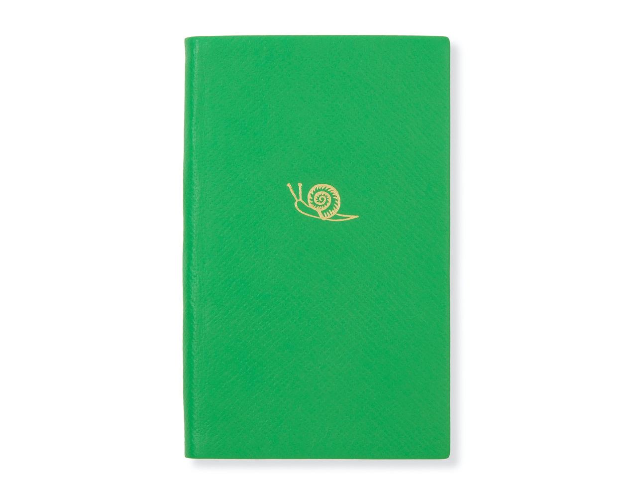 A green leather-bound notebook with a gold snail motif on the front from Smythson