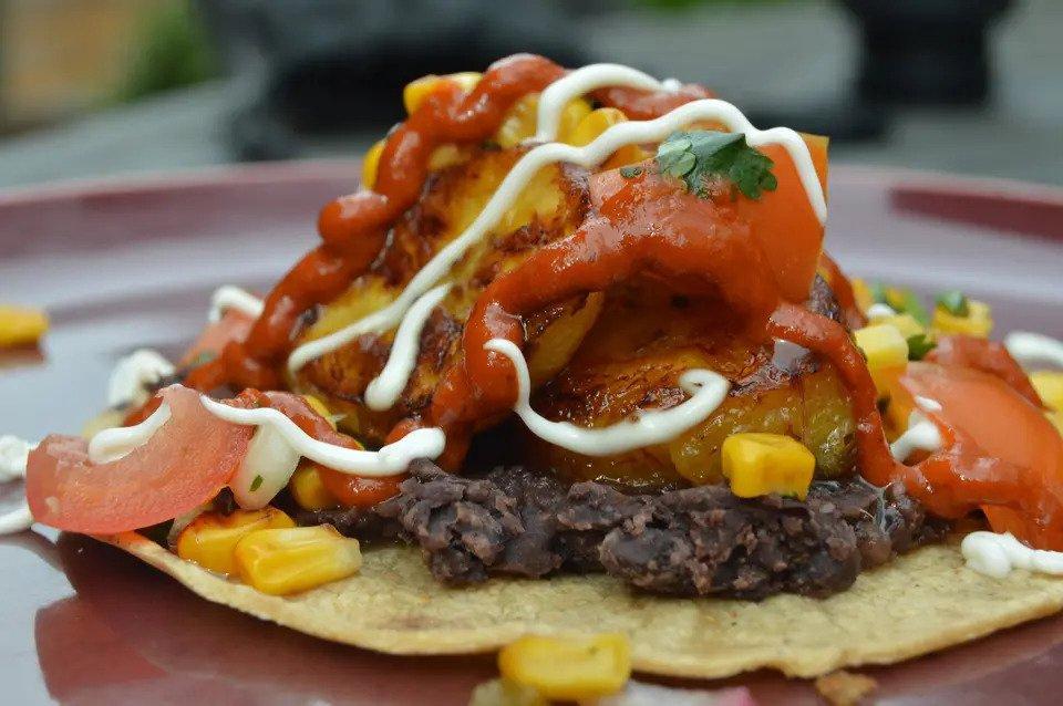 Open taco with roasted meat, corn, plantain and tomato