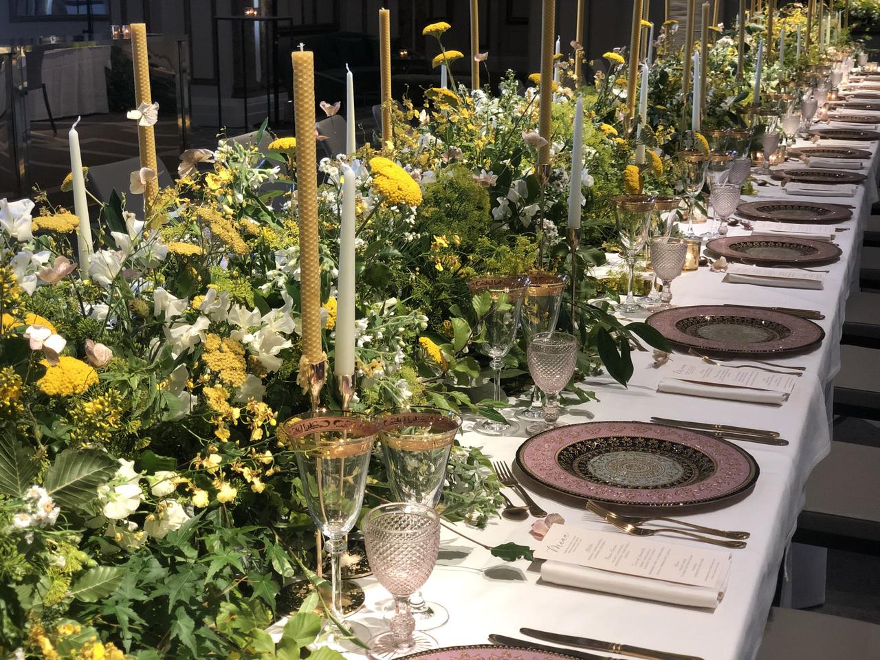 long white wedding table decorated with long tapered candles and green and yellow flowers
