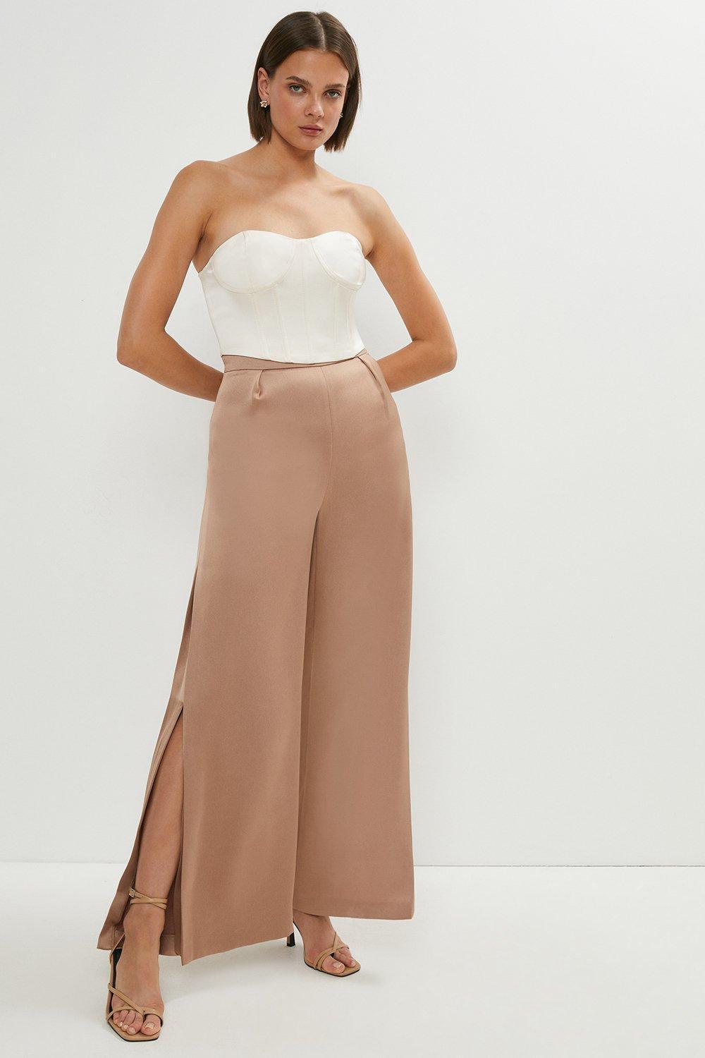 Model wearing a white corset and satin trousers