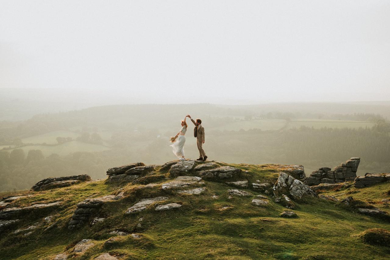 bride and groom dancing on a rock on a mountain