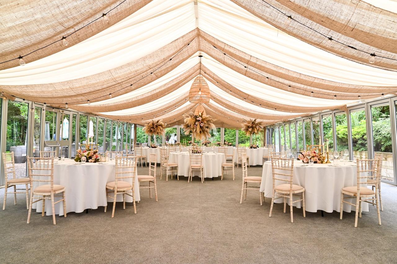 Interior of a marquee-style wedding venue with glass doors set up for a wedding reception.