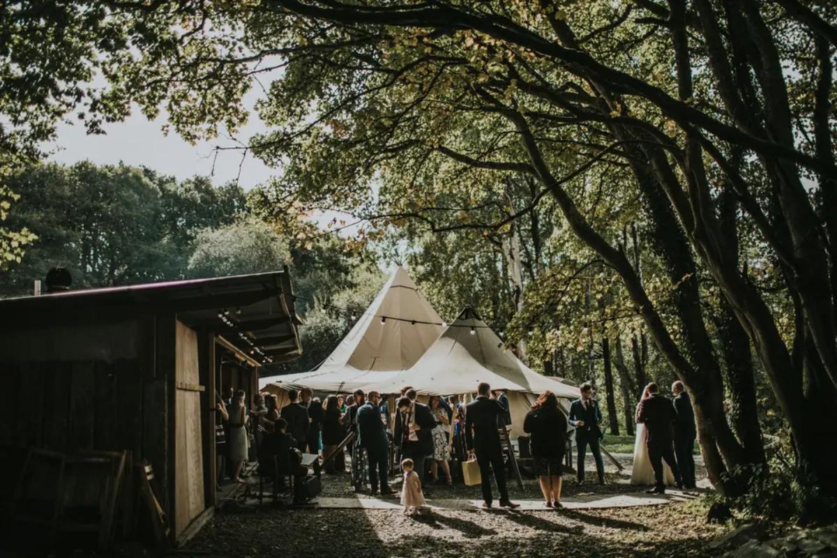 3 a group of guests at a weekend wedding standing under a tipi in summer at wedding venue fforest