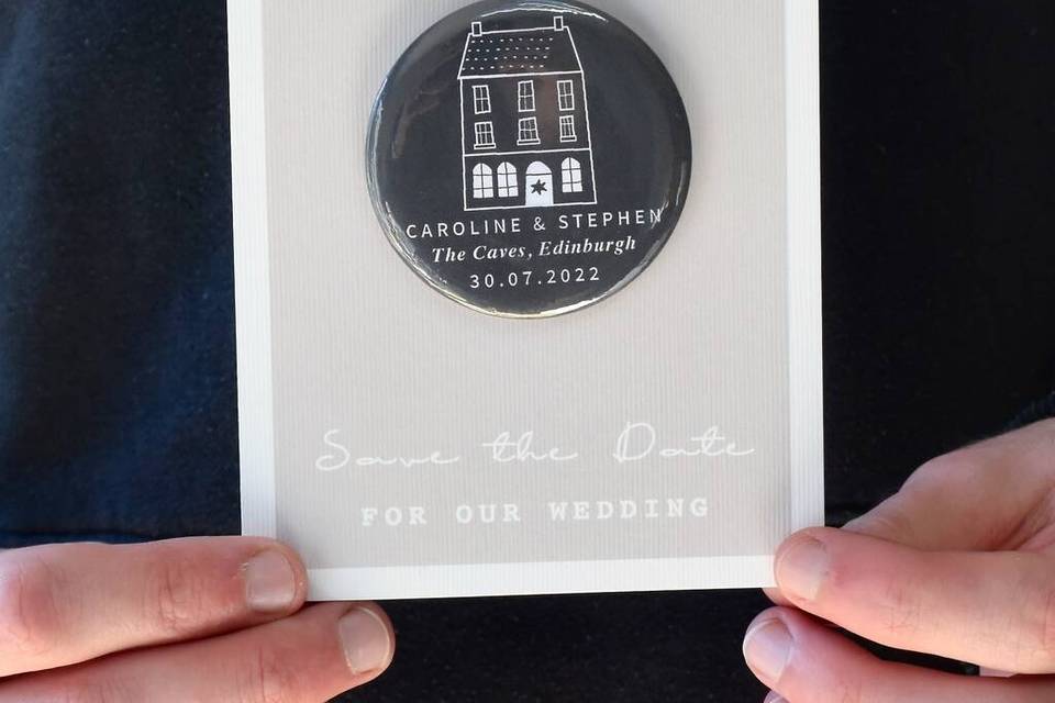 Black circular save the date magnet with hand drawn venue attached to a card reading 'put me on your fridge'