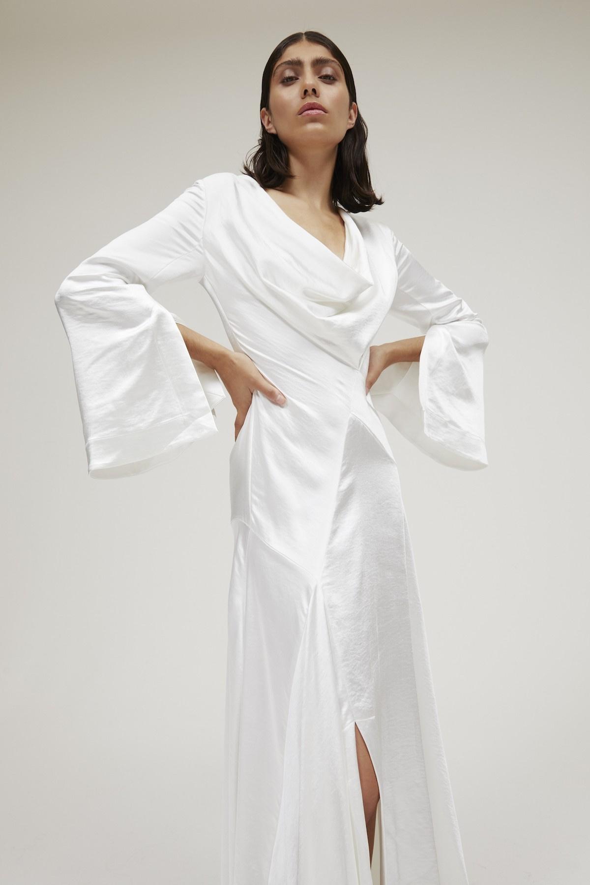 Image of a model wearing a beautifully draped wedding dress with chic bell sleeves