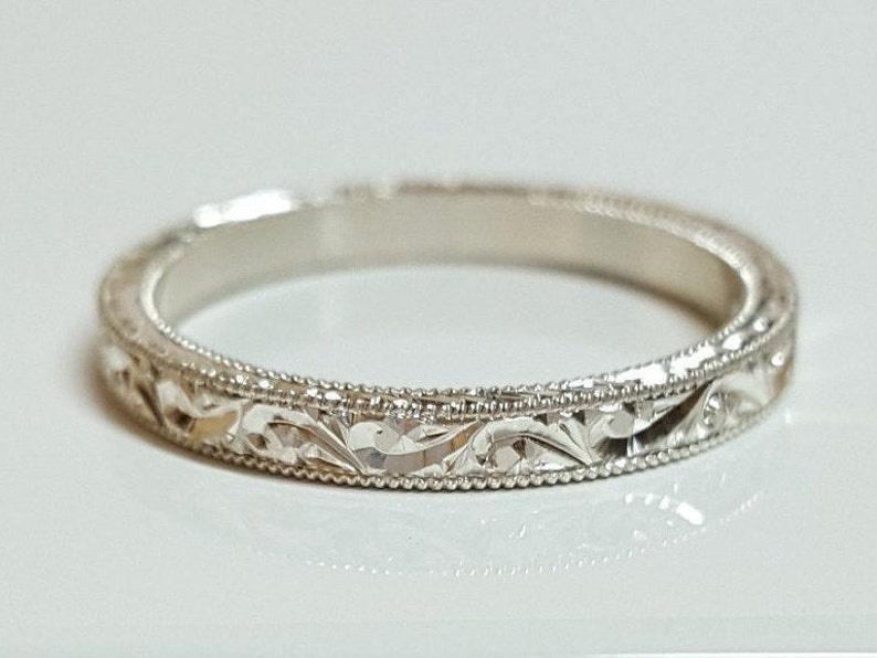 A platinum wedding band with an engraved swirly leafy design