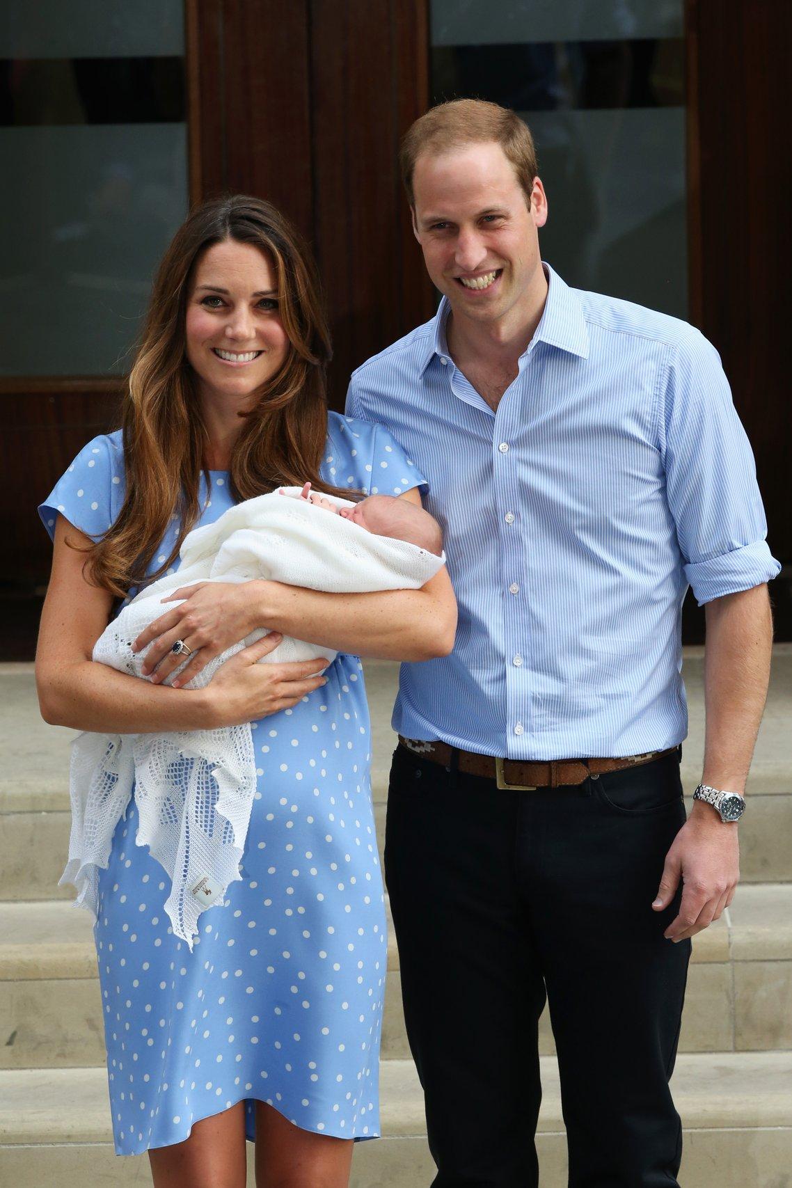 Kate Middleton and Prince William stand outside the hospital holding newborn Prince George