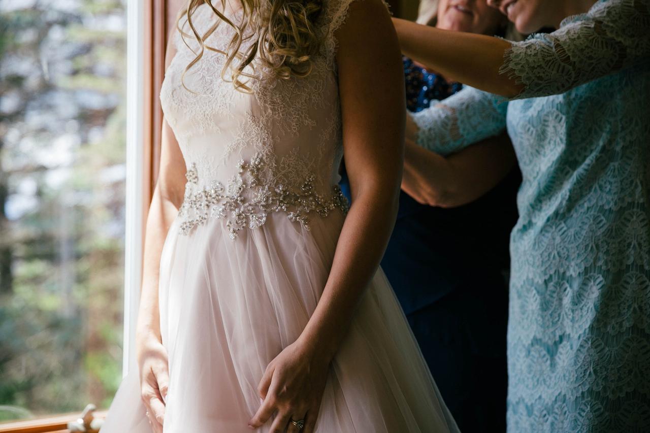 Bride being zipped into a dress