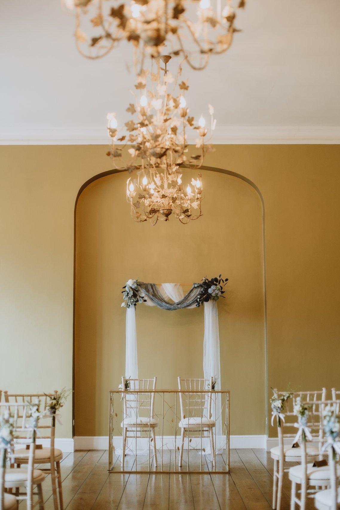 Simple metal arch behind two chairs at front of ceremony room 
