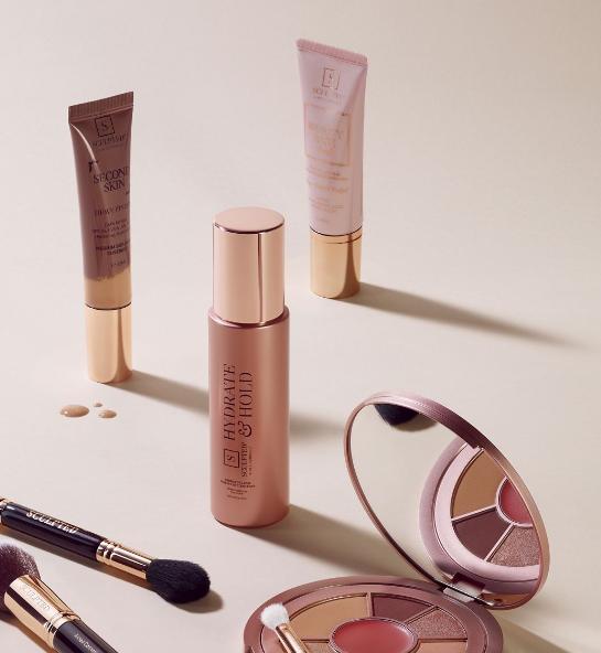 Different makeup products displayed on a table with the setting spray in the middle