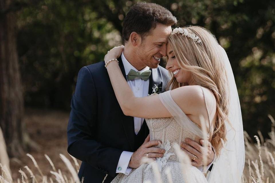 Stacey Solomon and Joe Swash embracing each other in their wedding clothes in a field