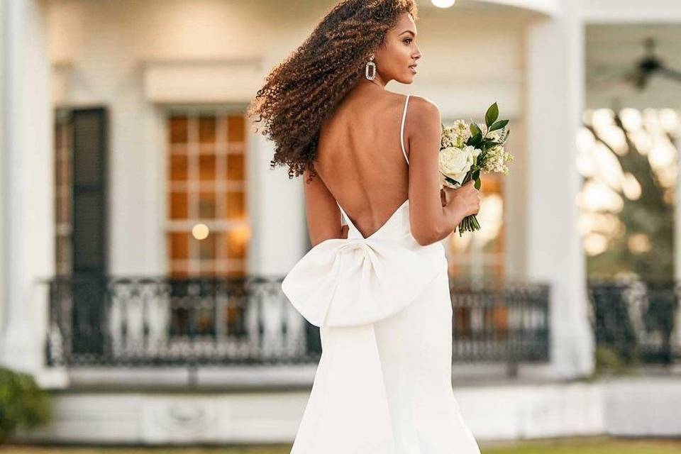 Bride with back to camera wearing a spaghetti strap dress with bow back detail