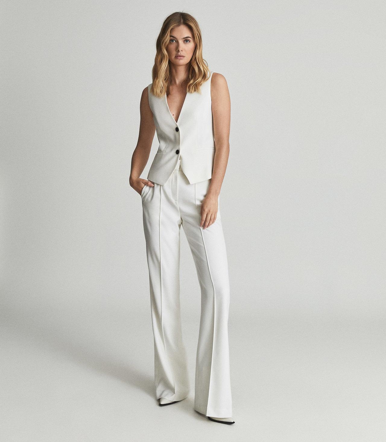 Model wearing a white waistcoat and trousers