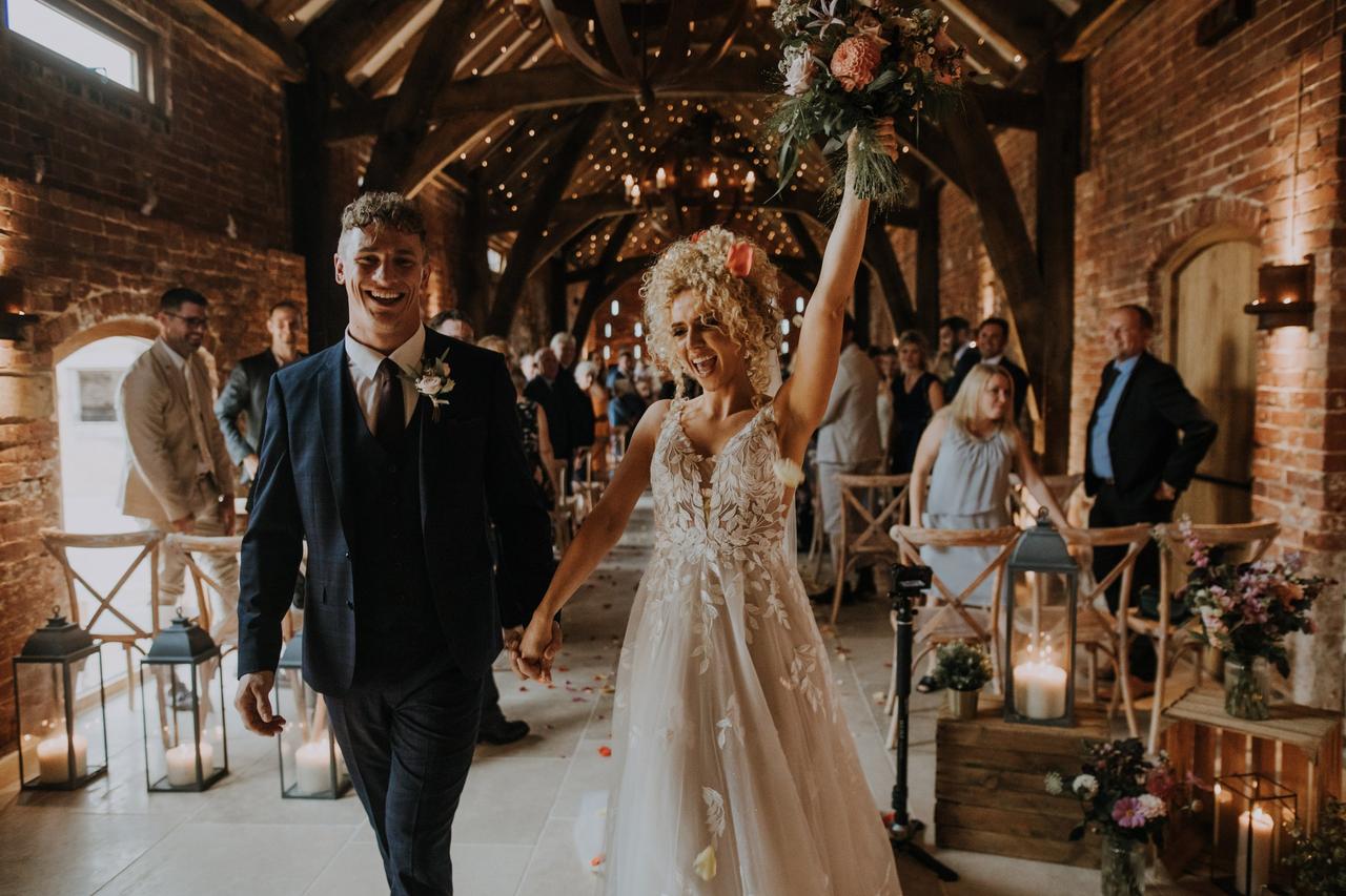 Bride and groom celebrate as they leave their wedding ceremony barn room