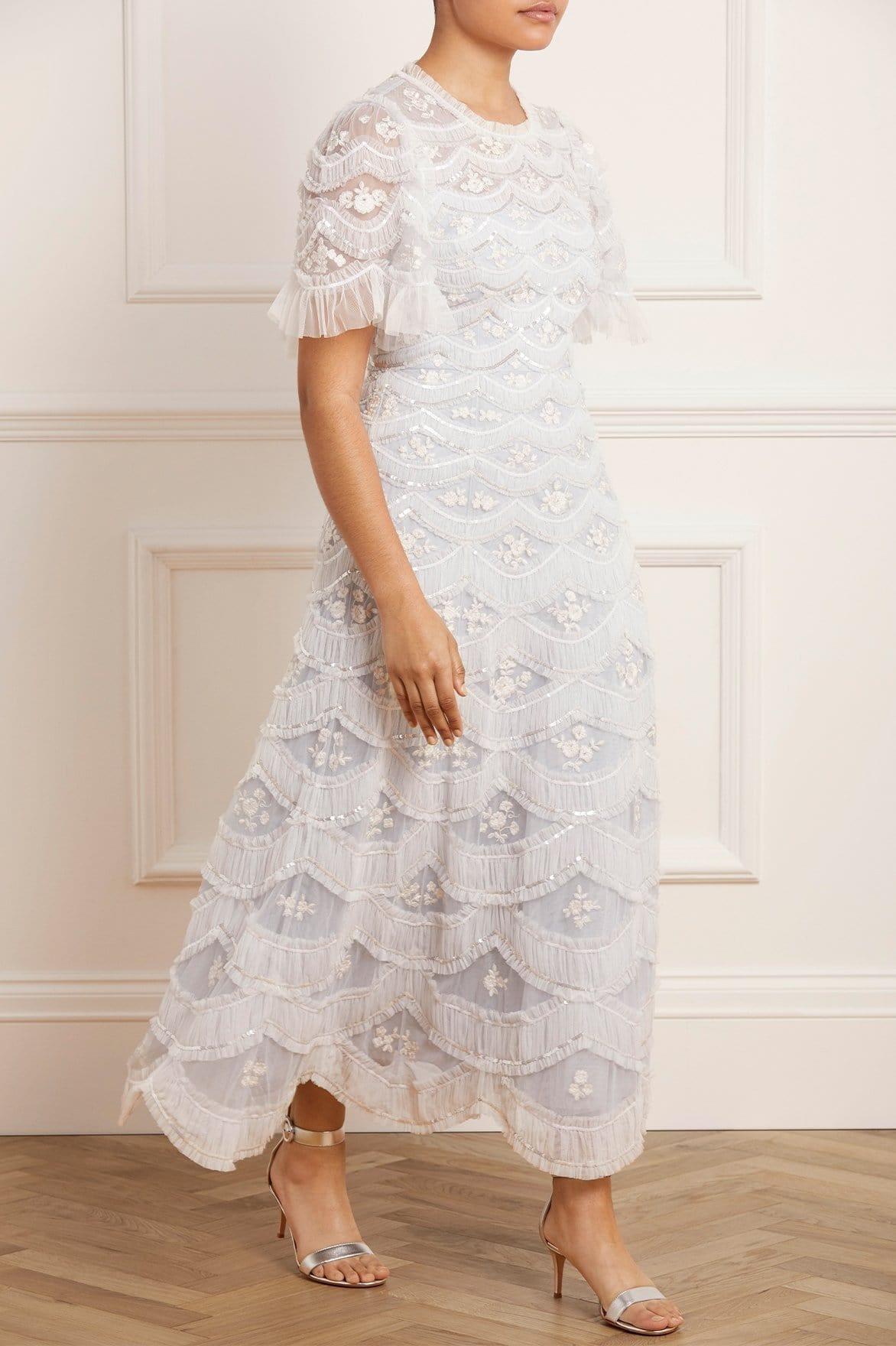 Image of a model wearing a midi-length gown with shimmering sequins and scalloped tulle details