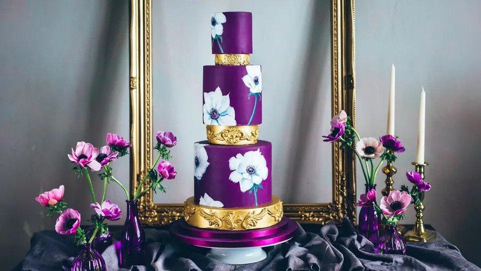 purple and gold wedding cake with glamorous gold spacers and hand painted large flowers