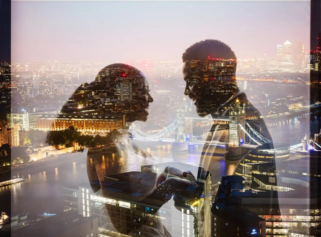 Newlyweds smile into each other's eyes as London Bridge shines in the background under city lights