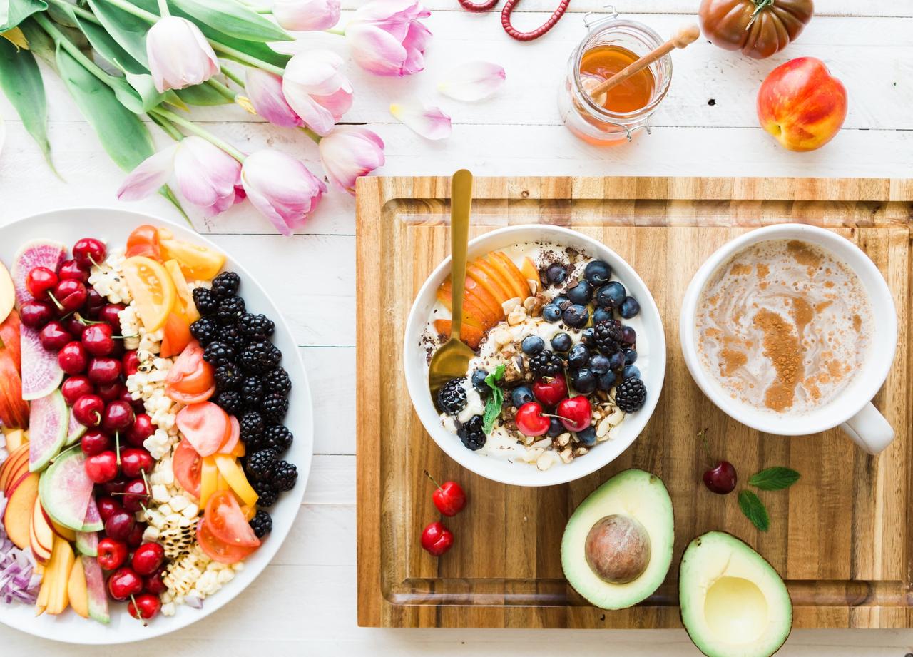 Flat lay of a healthy breakfast including a turmeric latte and a breakfast loaded with fruits such as berries