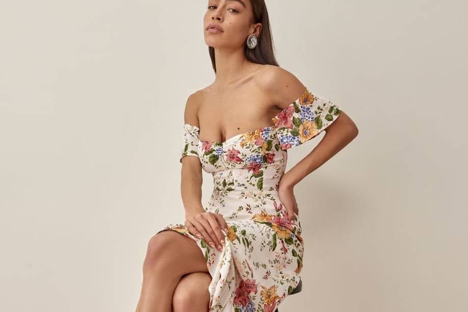 Bridesmaid seated on a stool wearing a boho bridesmaid dress decorated with a floral and butterfly print