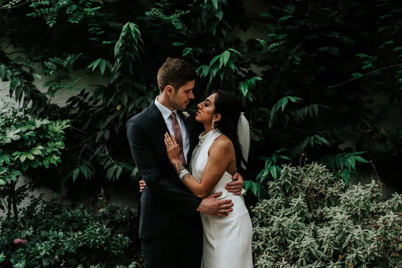 Les mariés s'embrassent à l'extérieur avec une riche toile de fond verdoyante