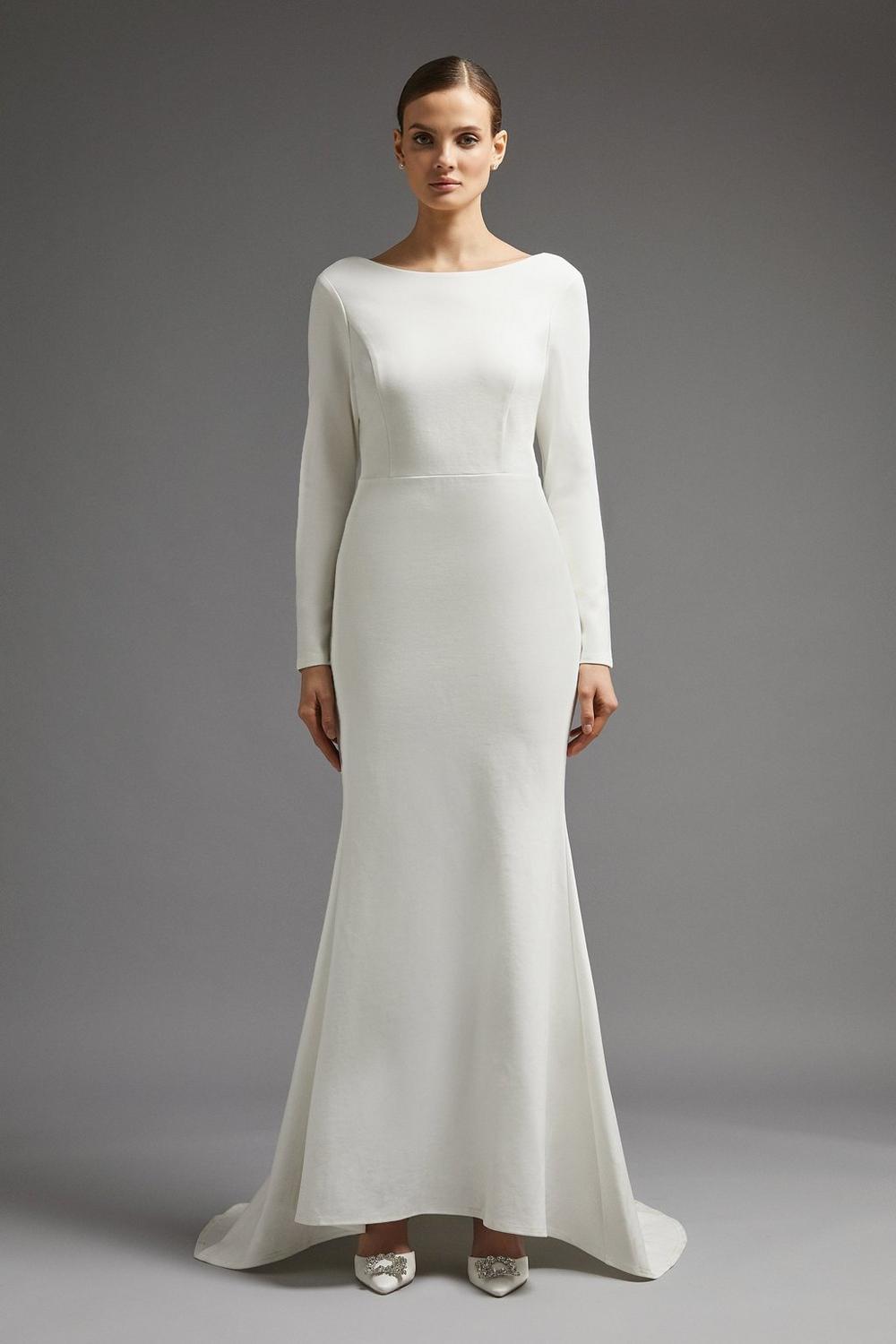 Model wearing a sleek long sleeved wedding dress