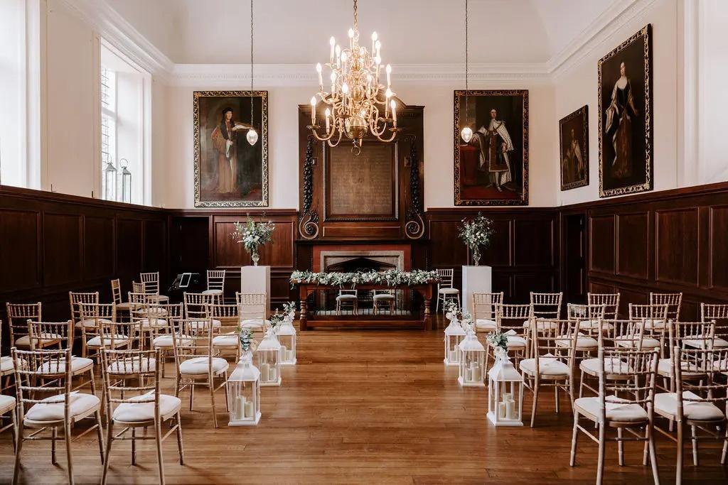 A stately historic hall decorated in oil paintings and wood panelling, set up for a civil ceremony