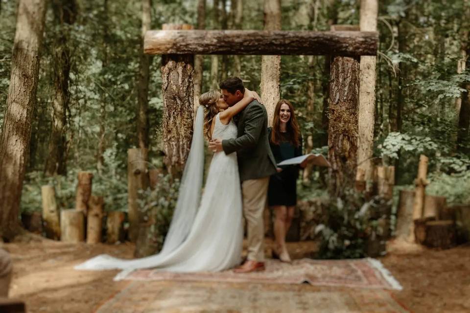 Bride and groom kissing at a woodland wedding ceremony 