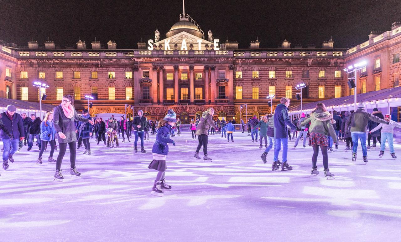 Outdoor ice skating rink with lots of people skating on the ice