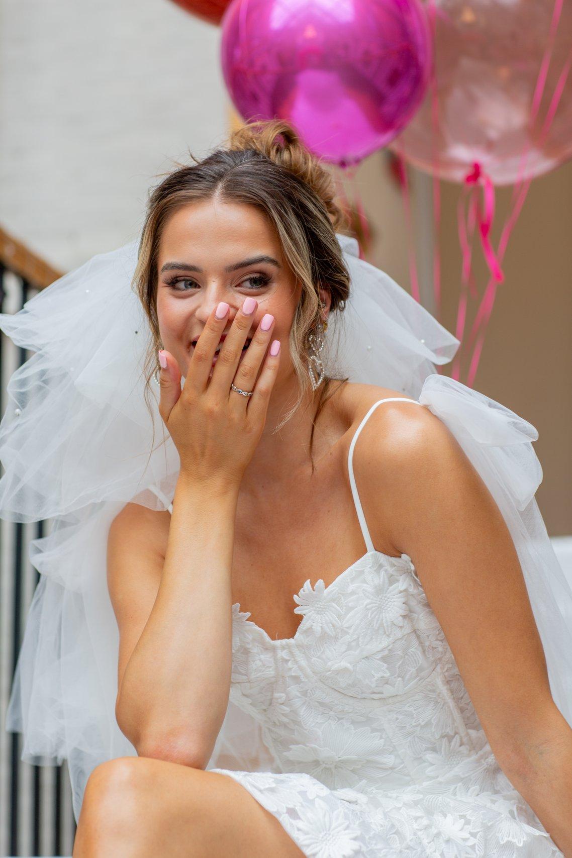 A bride giggling wearing a floral applique wedding dress