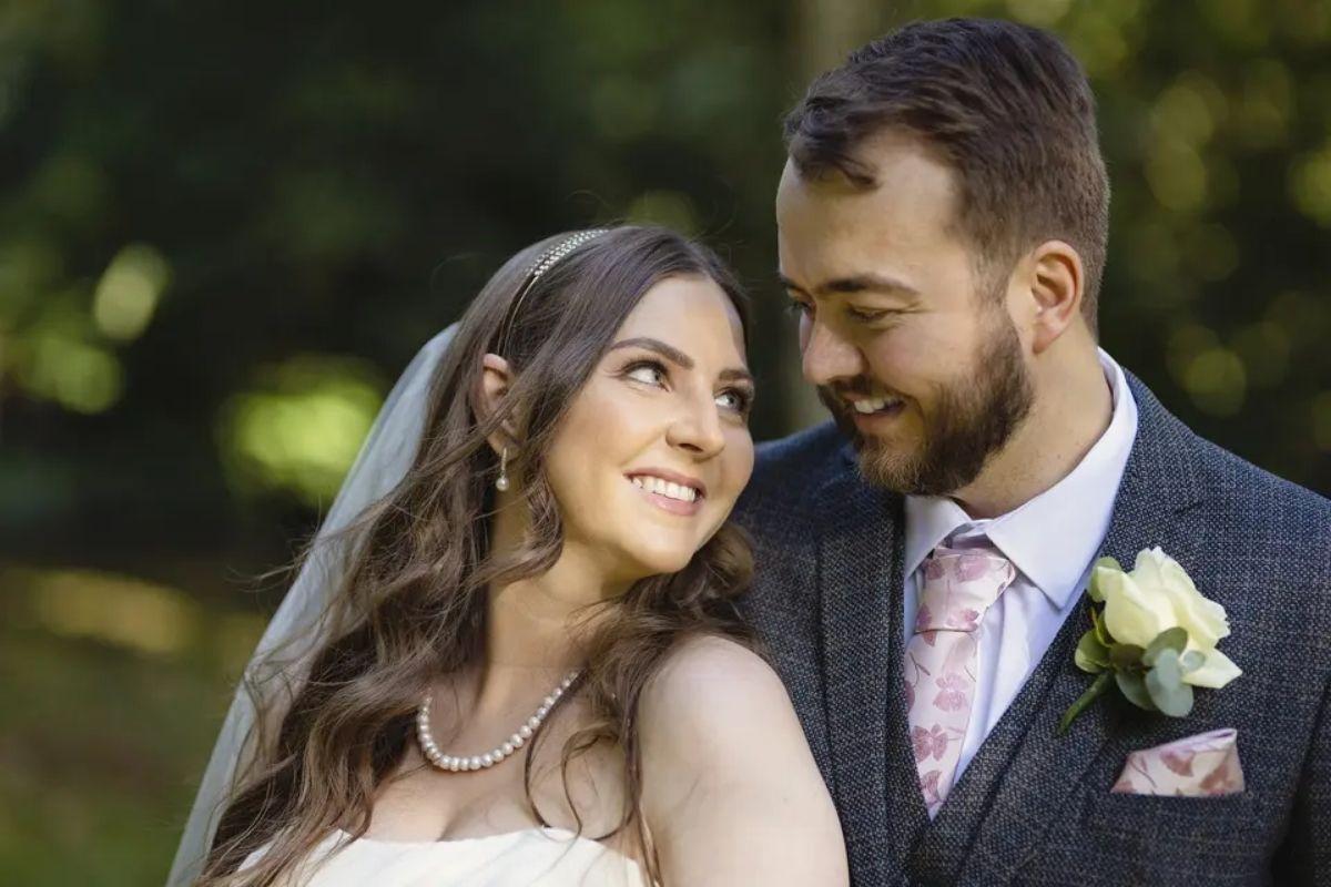 a bride leaning back and looking at her partner in the eye as they both smile and wear traditional wedding attire