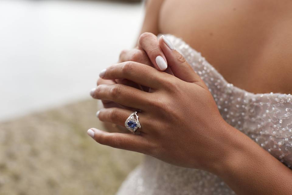 A bride wearing a white gold engagement ring with a blue sapphire and diamonds.