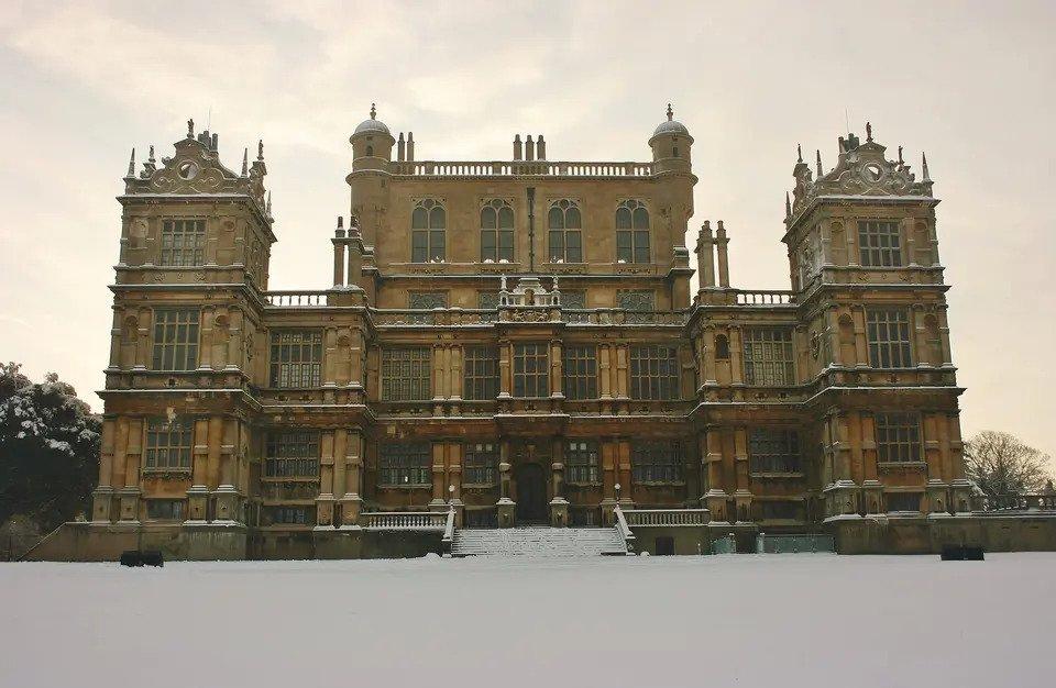 The sand-coloured exterior of Wollaton Hall surrounded by snow