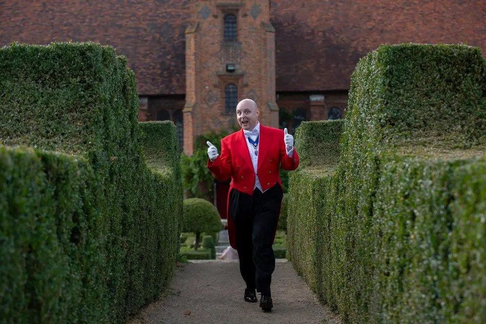 Wedding toastmaster walking through the grounds of a  venue giving a double thumbs up