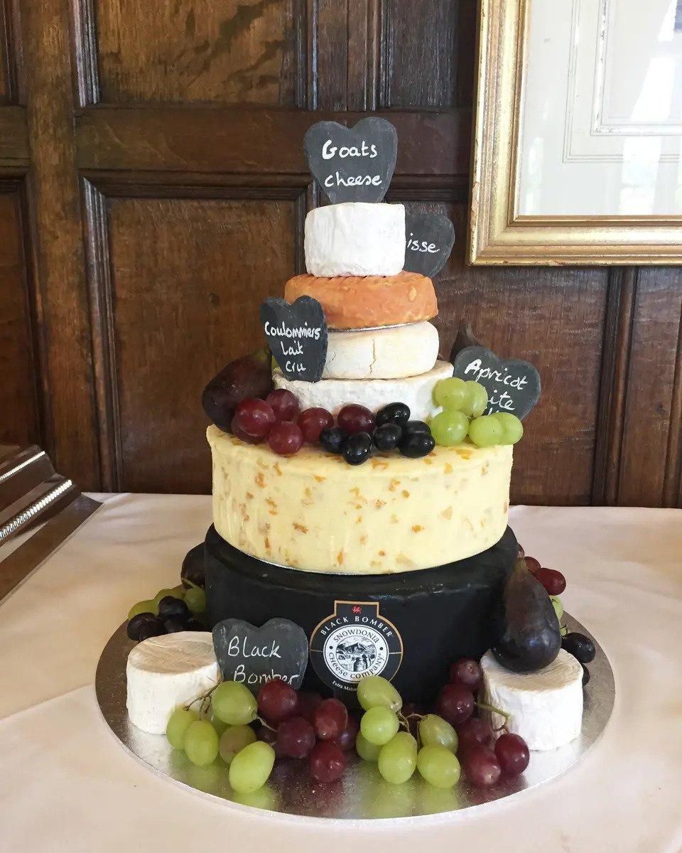 Six tiers of different cheeses decorated with red and green grapes