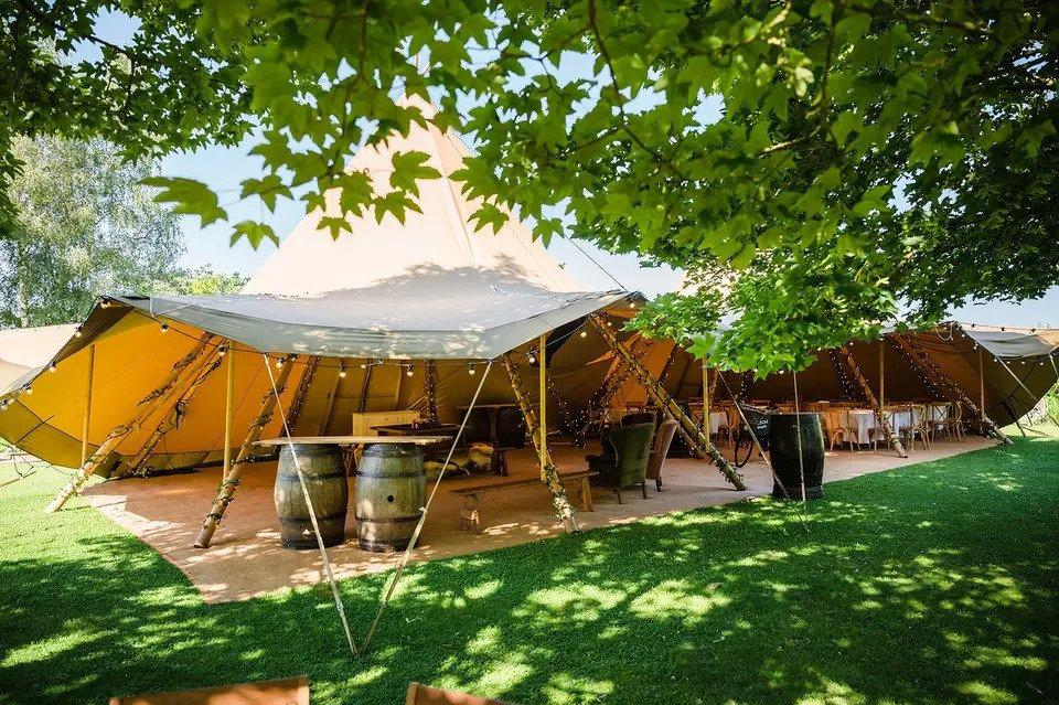 Tipi wedding venues decorated with fairy lights and barrels and surrounded by greenery