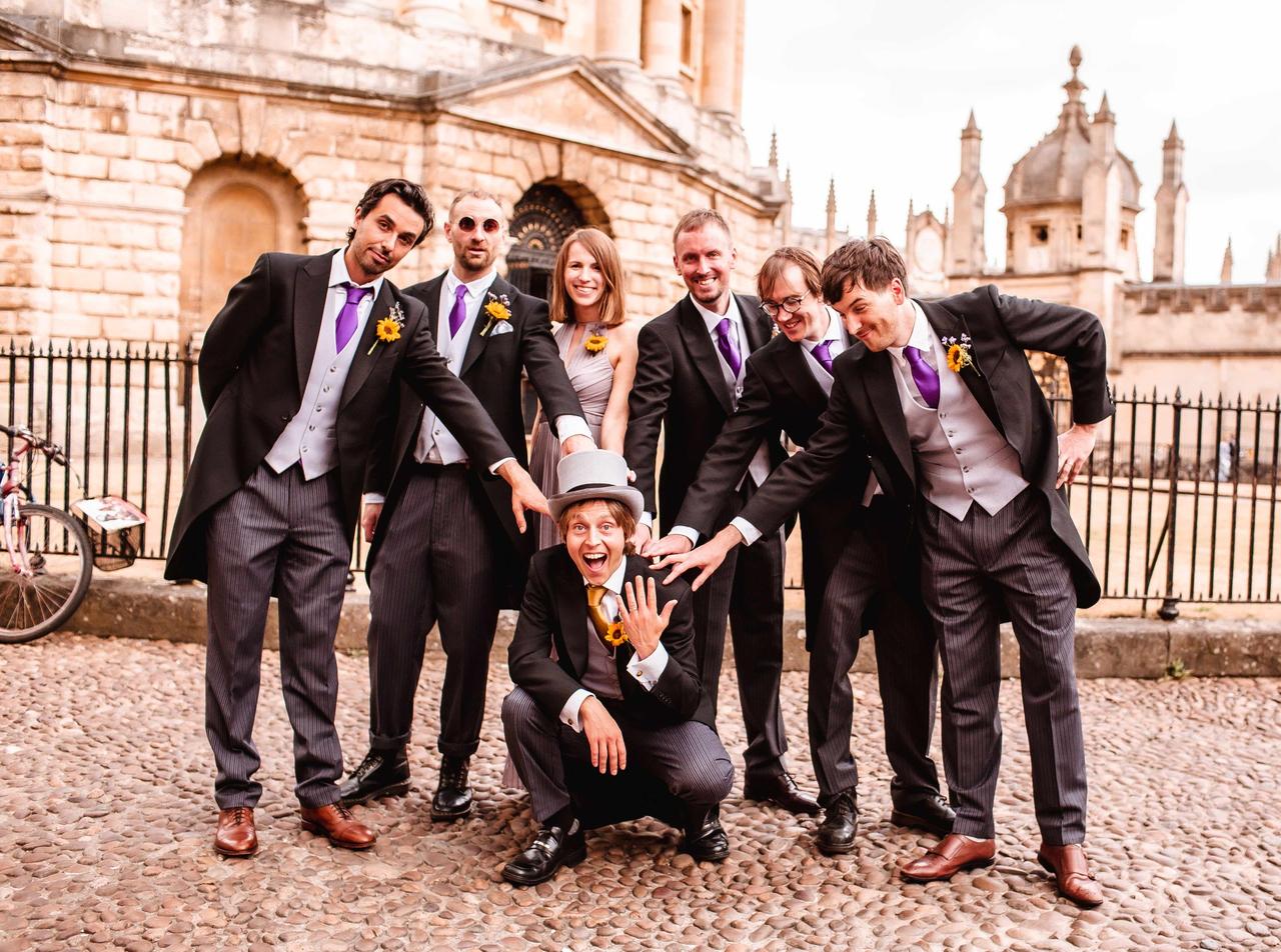 A groom crouches in front of his groomsmen