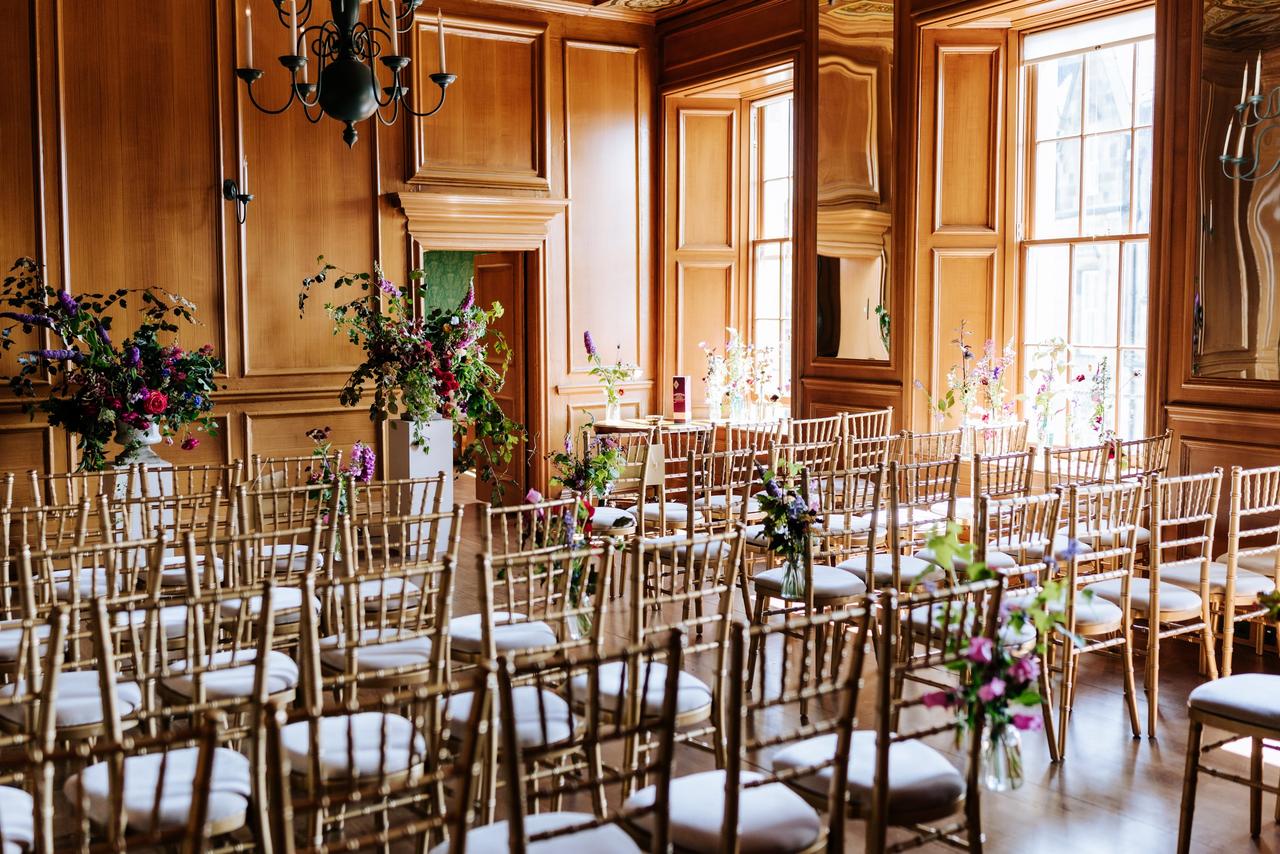 An oak panelled ceremony room with beautiful floral displays and chiavari chairs arranged for a civil ceremony.