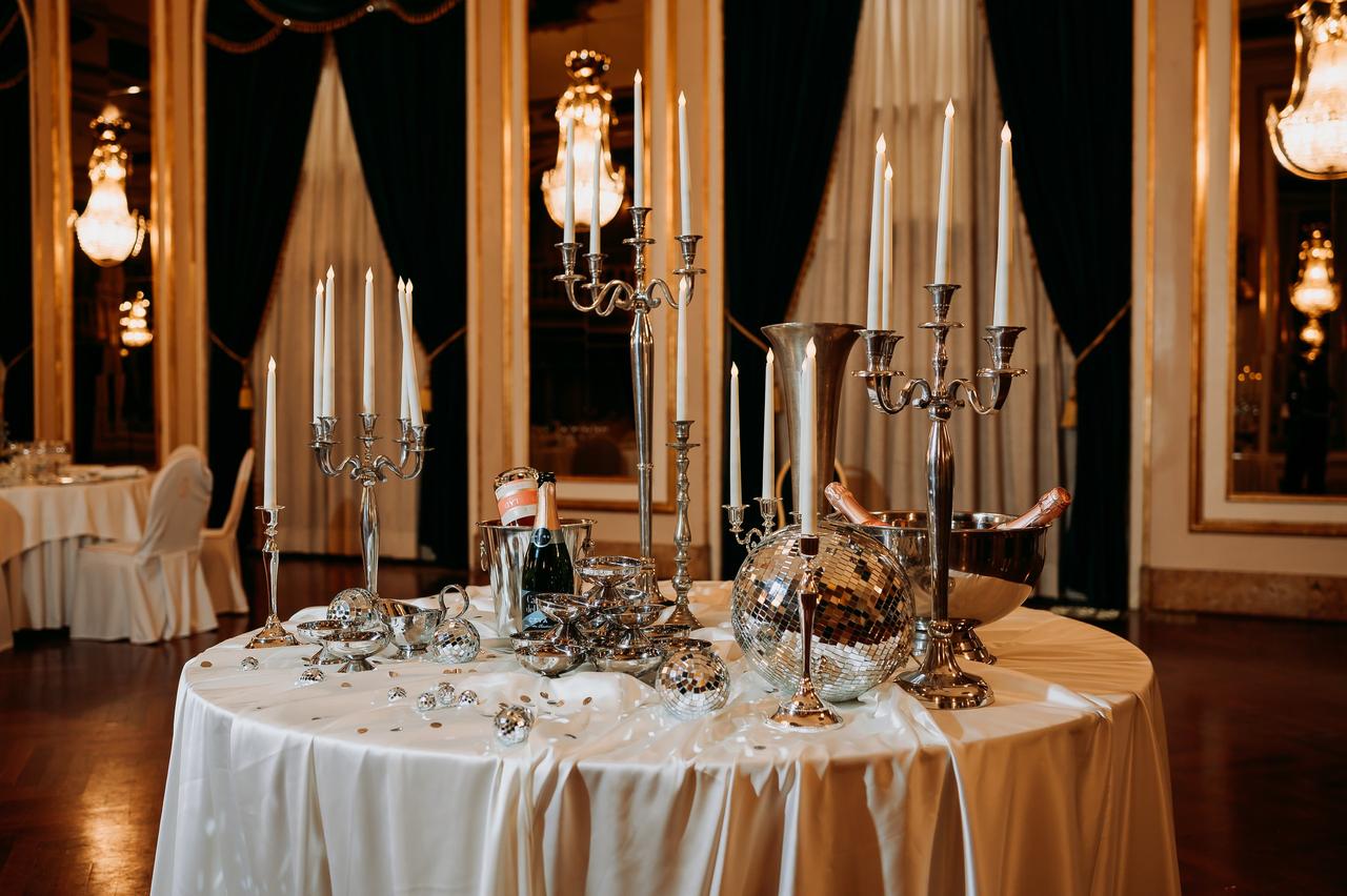 messy round white wedding table with tall tapered candles in vintage silverware and a disco ball