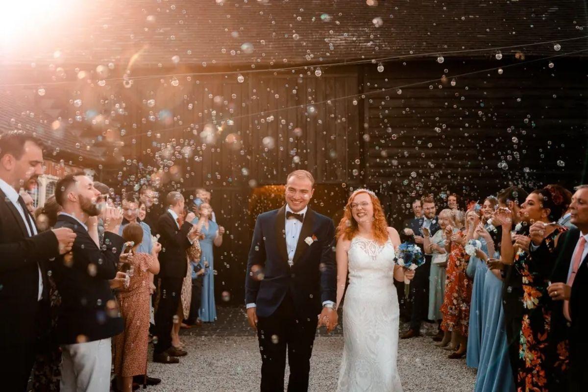 a bride and groom walking through their recessional line with the sun shining in the corner