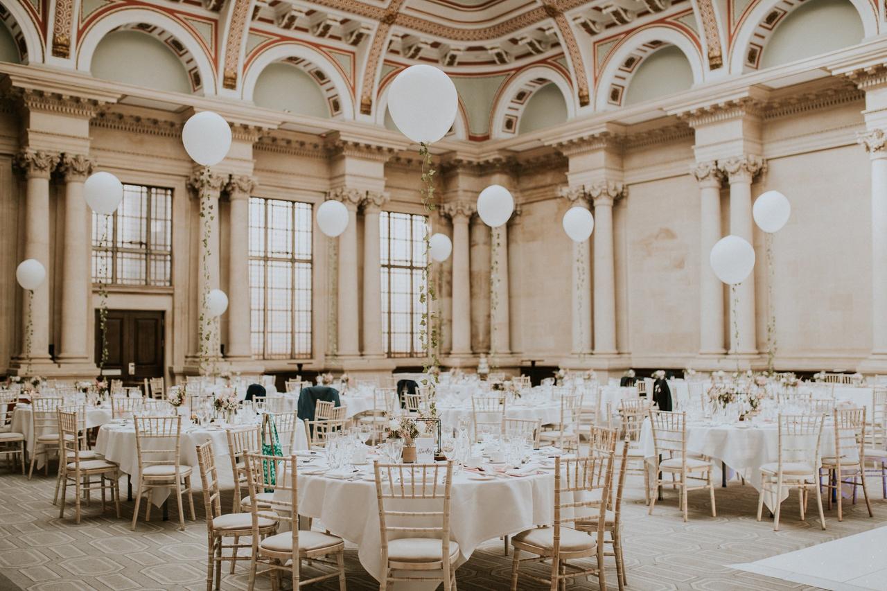 interior of a grand ballroom hotel wedding venue with high ceiling and round tables with chiavari chairs.
