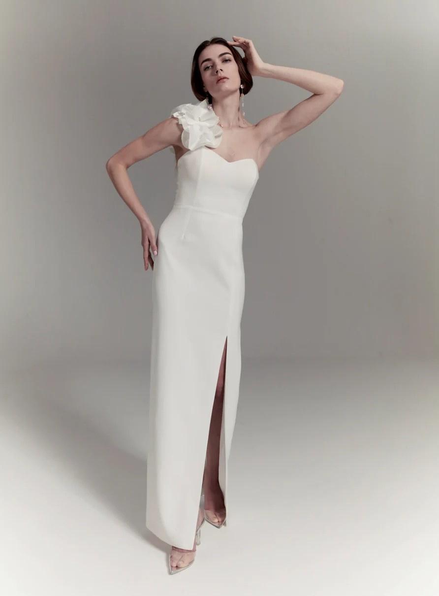 Model wearing a wedding dress with a 3D floral one shoulder design
