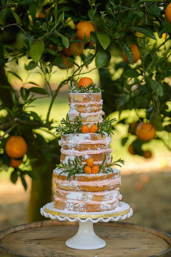 Three tiered naked rustic wedding cake with citrus fruits