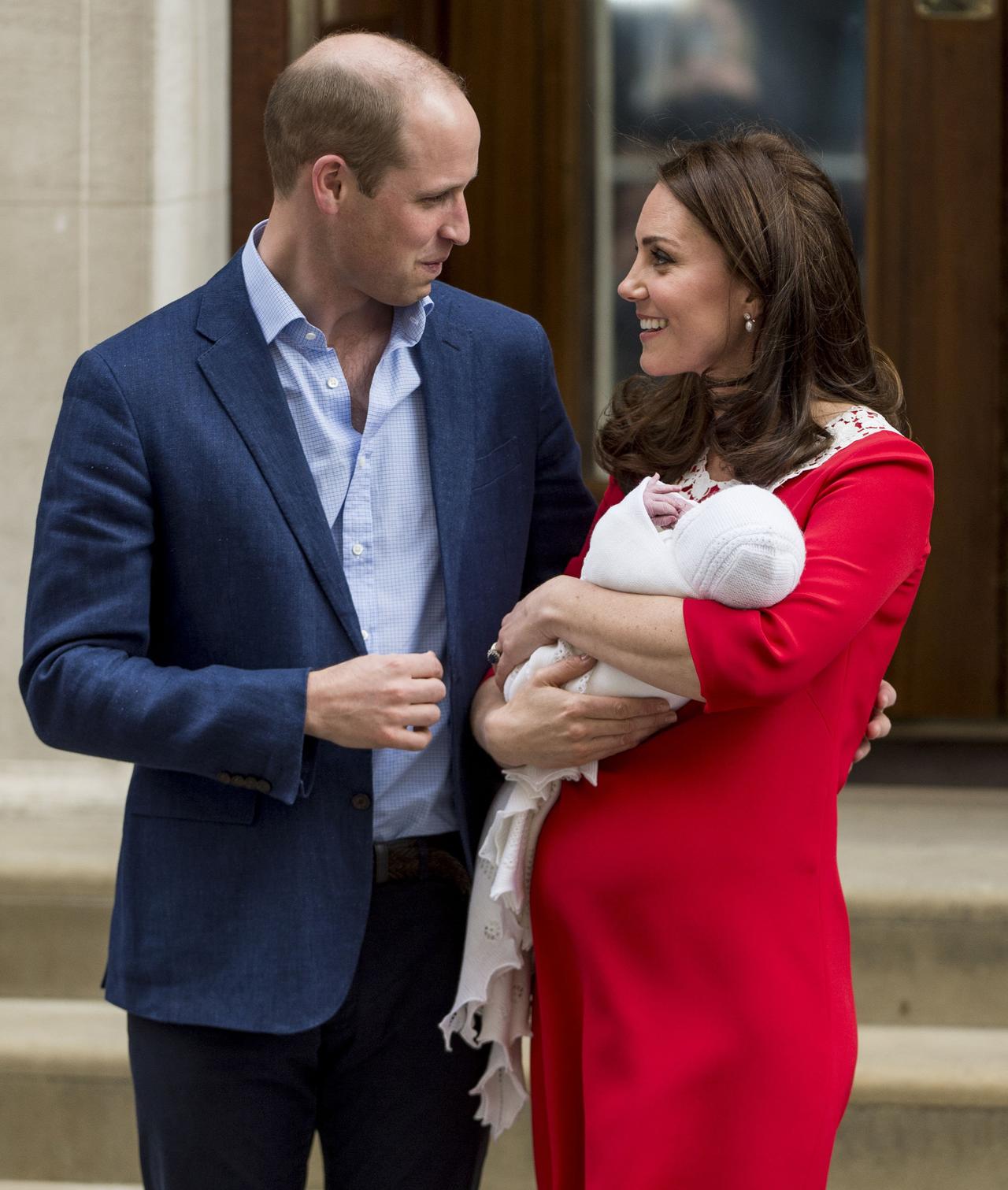 Kate Middleton and Prince William look at each other as they hold Prince Louis