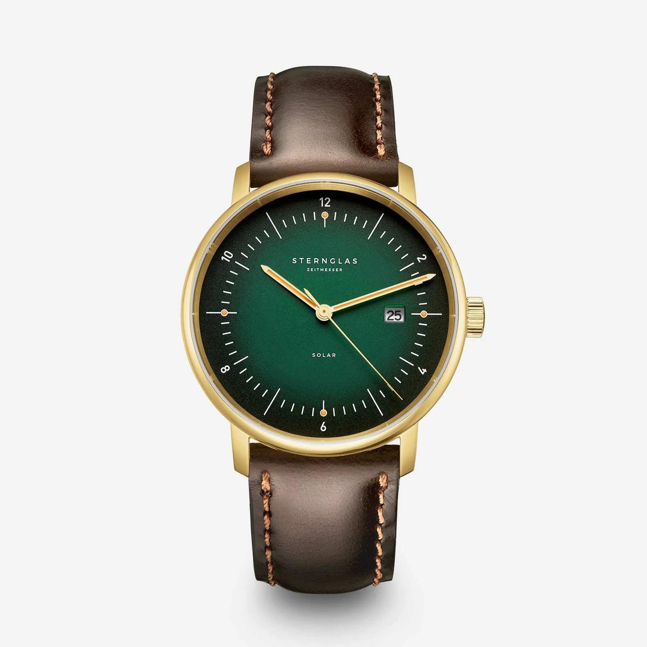 A watch with brown leather strap and gold and dark green face.