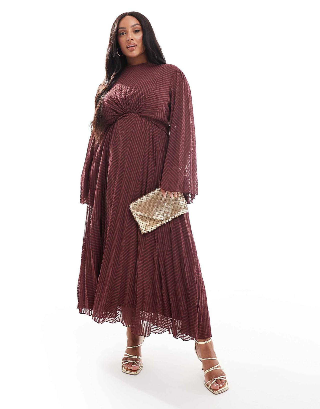 A plus size wedding guest wearing a burgundy maxi dress with a black chevron print and long flared sleeves. She's wearing it with silver accessories.